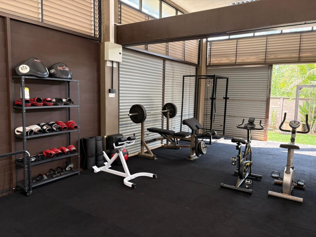 Squat rack, bench press, spin bikes, and a wall of Muay Thai gloves at Bambu
