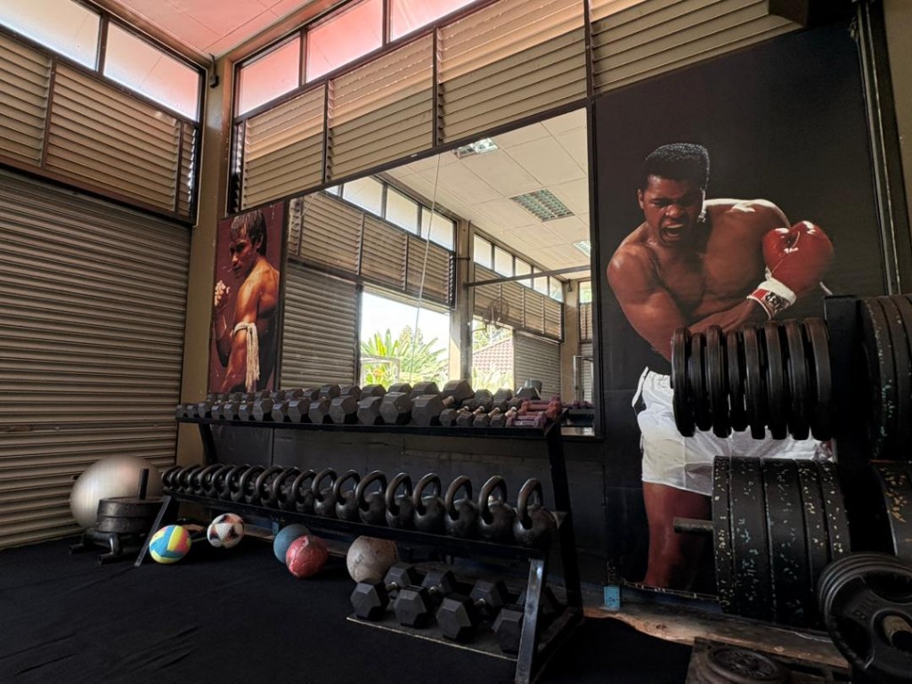 Dumbbell rack, kettlebells and medicine balls beside the Muhammad Ali mural at Bambu