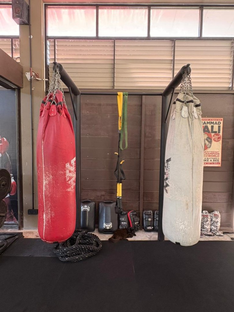 Two Muay Thai heavy bags with battle rope, gloves, and shin pads at Bambu