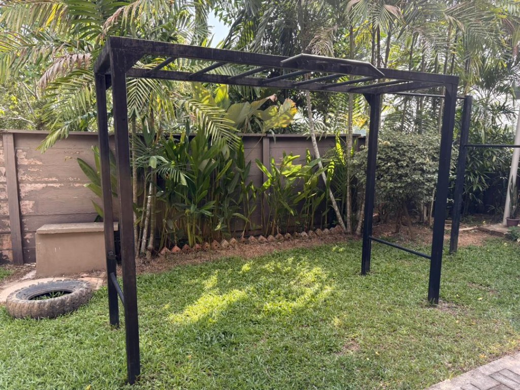 Custom-built outdoor pull-up and dip rig surrounded by tropical plants at Bambu